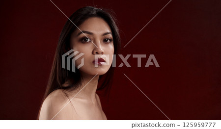 Young Asian Woman Posing on Dark Red Background in Studio Young Asian Woman Posing on Dark Red Background in Studio 125959777