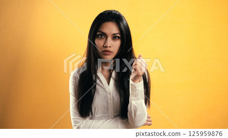Young Asian Woman Gesturing on Yellow Background in Studio with Copyspace 125959876