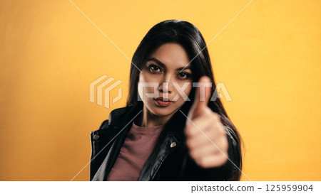 Young Asian Woman Showing Thumbs Up on Yellow Background 125959904