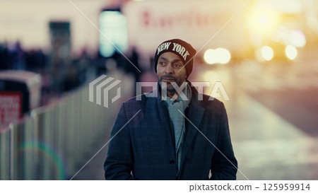 Man wearing New York beanie walking in Manhattan at dusk 125959914