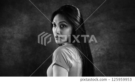 Asian woman turning towards camera in dramatic lighting 125959953