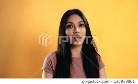 Young Asian Woman Showing Surprise Expression on Yellow Background 125959961
