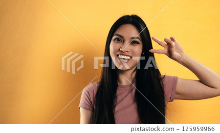 Young Asian Woman Gesturing Three with Fingers on Yellow Background 125959966