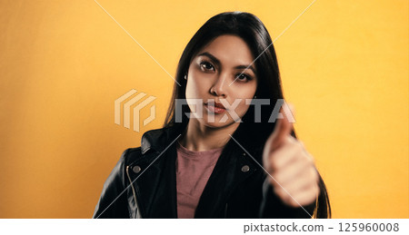 Young Asian Woman Pointing Finger at the Viewer on Yellow Background 125960008
