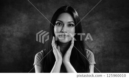 Young woman holding her face with hands, black and white portrait 125960010