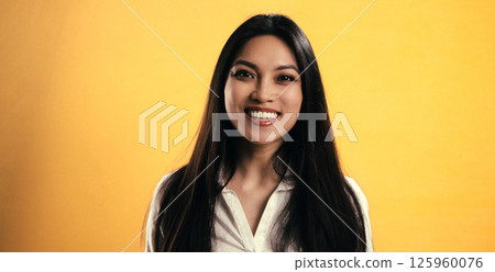 Young Asian Woman Smiling on Yellow Background with Copy Space Young Asian Woman Smiling on Yellow Background with Copy Space 125960076