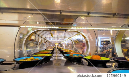 Running sushi bar transporting plates of food on a conveyor belt Running sushi bar transporting plates of food on a conveyor belt 125960149