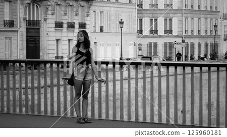 Young woman standing on bridge in Paris enjoying urban view 125960181