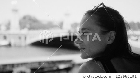 Woman enjoying Paris from Seine river contemplating bridge in black and white Woman enjoying Paris from Seine river contemplating bridge in black and white 125960191