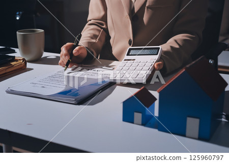 Female Real Estate Broker presenting and advised to model home and building project detail in the office, sign purchase sales contract, agreements concerned mortgage loan offer and insurance. 125960797