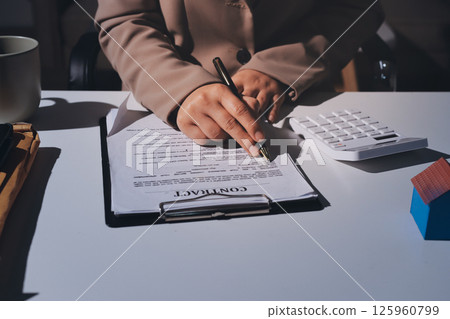 Female Real Estate Broker presenting and advised to model home and building project detail in the office, sign purchase sales contract, agreements concerned mortgage loan offer and insurance. 125960799