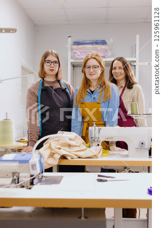 Three female seamstresses work for production of clothing. industrial equipment sewing machines. Three female seamstresses work for production of clothing. industrial equipment sewing machines. 125961128