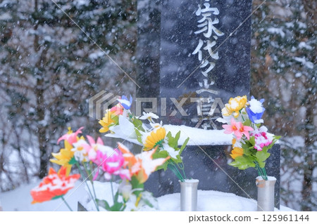 Gravestone and snow-covered Buddhist flowers Gravestone and snow-covered Buddhist flowers 125961144