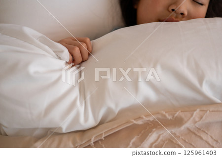 A girl sleeping soundly in a quiet bedroom, holding a white futon A girl sleeping soundly in a quiet bedroom, holding a white futon 125961403