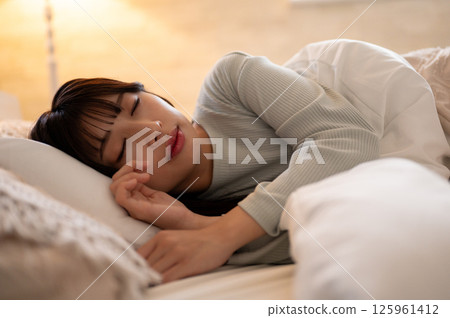 一名女子在夜燈下趴著睡覺，看起來很放鬆 125961412