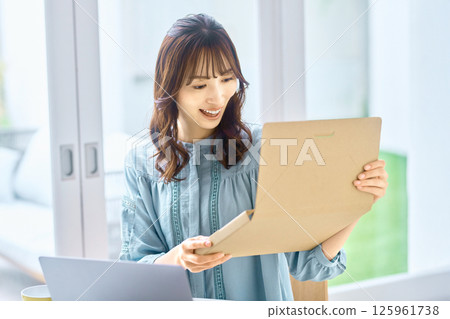 一位年輕女子一邊查看電腦一邊檢查行李 125961738
