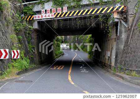A car approaching a curve on a prefectural road that passes under a railway line A car approaching a curve on a prefectural road that passes under a railway line 125962007