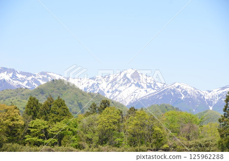 Snow-covered Mt. Tanigawa and rural scenery 125962288