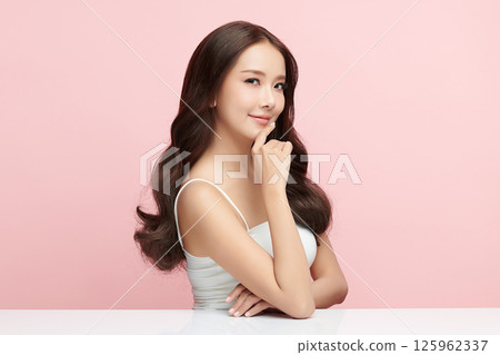A beautiful young Asian woman with clean, fresh skin against a pink background. Skincare, facial treatment, cosmetology, beauty, and spa. An elegant portrait of an Asian woman. 125962337