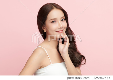 A beautiful young Asian woman with clean, fresh skin against a pink background. Skincare, facial treatment, cosmetology, beauty, and spa. An elegant portrait of an Asian woman. 125962343