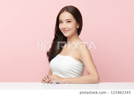 A beautiful young Asian woman with clean, fresh skin against a pink background. Skincare, facial treatment, cosmetology, beauty, and spa. An elegant portrait of an Asian woman. 125962345