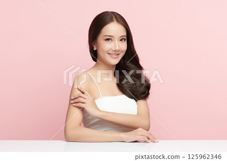 A beautiful young Asian woman with clean, fresh skin against a pink background. Skincare, facial treatment, cosmetology, beauty, and spa. An elegant portrait of an Asian woman. 125962346
