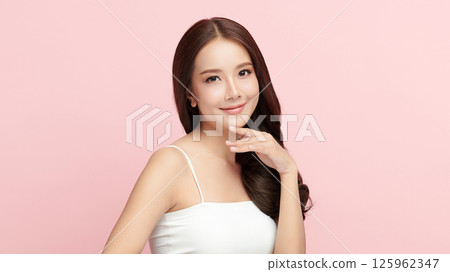 A beautiful young Asian woman with clean, fresh skin against a pink background. Skincare, facial treatment, cosmetology, beauty, and spa. An elegant portrait of an Asian woman. A beautiful young Asian woman with clean, fresh skin against a pink background. Skincare, facial treatment, cosmetology, beauty, and spa. An elegant portrait of an Asian woman. 125962347