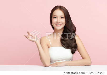 A beautiful young Asian woman with clean, fresh skin against a pink background. Skincare, facial treatment, cosmetology, beauty, and spa. An elegant portrait of an Asian woman. 125962350