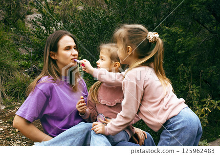 mother with daughter outside doing makeup having fun 125962483