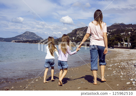 mother with twins daughters on beach 125962510