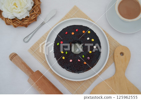 a large chocolate-glazed topped with chocolate sprinkles a large chocolate-glazed topped with chocolate sprinkles 125962555