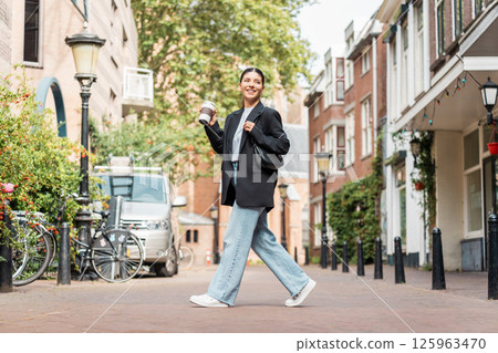 On the move in the moment as attractive woman walks through scenic streets balancing style ambition and peace On the move in the moment as attractive woman walks through scenic streets balancing style ambition and peace 125963470