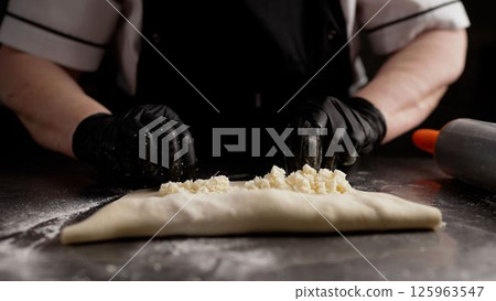 Baker making khachapuri: folding dough on metal table Baker making khachapuri: folding dough on metal table 125963547
