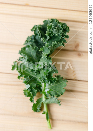 Fresh green Kale leaf salad vegetable on wooden background. 125963652
