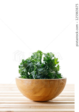 Fresh green Kale leaf salad vegetable in wooden bowl on white background. 125963675