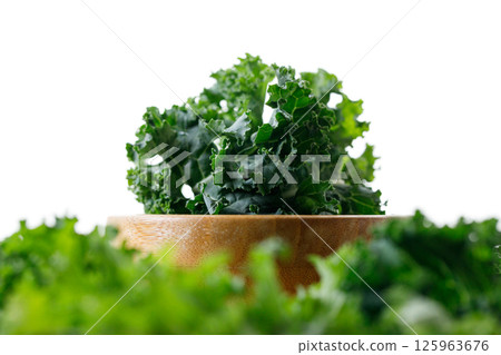 Fresh green Kale leaf salad vegetable in wooden bowl on white background. 125963676