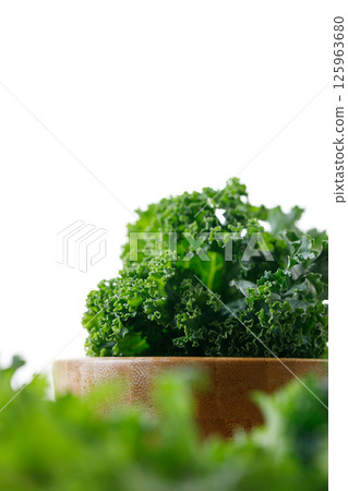 Fresh green Kale leaf salad vegetable in wooden bowl on white background. 125963680