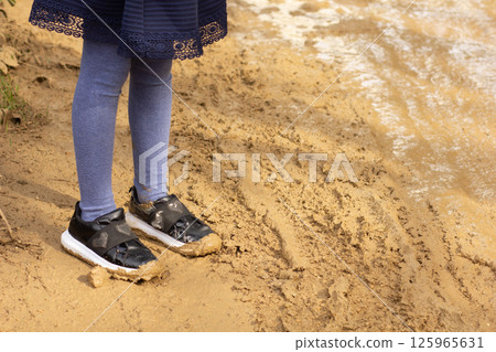 Child legs with shoes in mud outside Child legs with shoes in mud outside 125965631