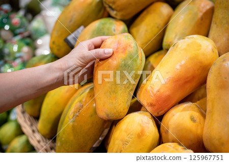 Tourist hand checking ripe soft papaya selecting best piece at market fruit counter, food shopping Tourist hand checking ripe soft papaya selecting best piece at market fruit counter, food shopping 125967751