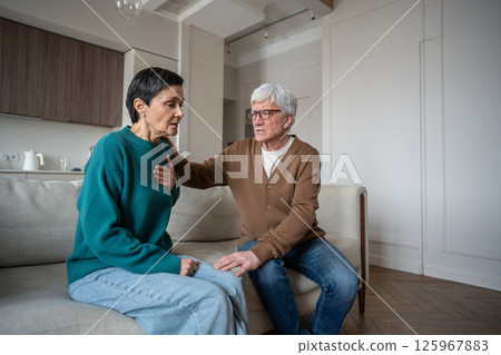 Woman overwhelmed by sudden grief clutches chest in shock, distressed man embraces with concern 125967883