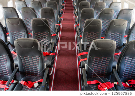 Empty interior of cabin of airplane with rows of black and red seats, high angle view 125967886