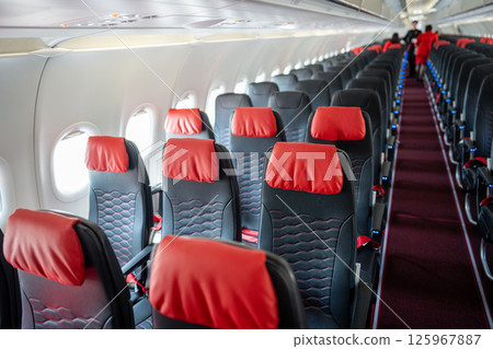 Empty interior of cabin of airplane with rows of black and red seats in daytime before the flight Empty interior of cabin of airplane with rows of black and red seats in daytime before the flight 125967887
