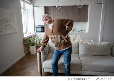 Aging pensioner attempts standing despite excruciating back pain, disc hernia and back spasm Aging pensioner attempts standing despite excruciating back pain, disc hernia and back spasm 125968476