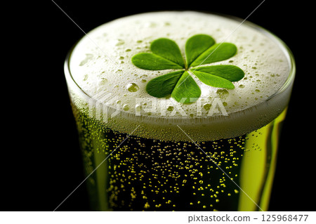 Bubbling green beer with frothy head and clover leaf garnish in clear glass 125968477