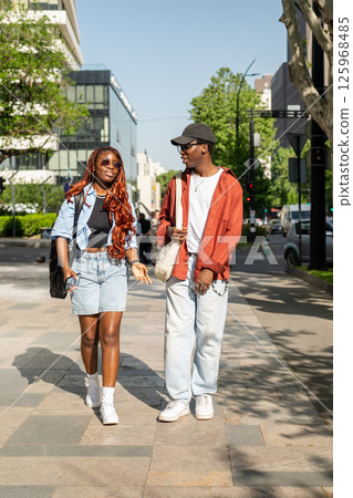 Smiling joyful romantic African American couple strolls through city streets, laughing and joking Smiling joyful romantic African American couple strolls through city streets, laughing and joking 125968485