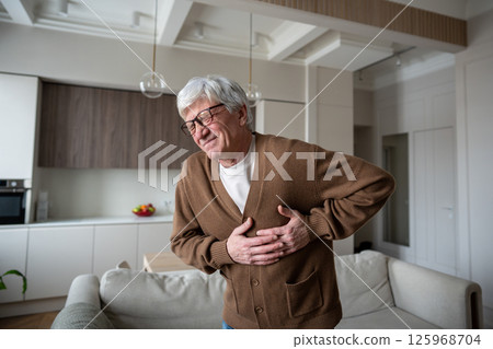 Frowning in pain old man gasps for air with crush chest pain. Acute coronary syndrome, heart attack 125968704