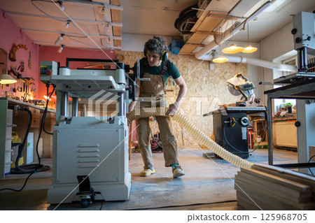 Concentrated carpenter attach air extractor vacuum hose to planer, ensuring dust removal in workshop Concentrated carpenter attach air extractor vacuum hose to planer, ensuring dust removal in workshop 125968705