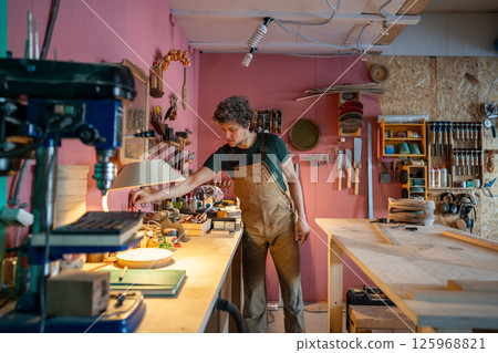 Attentive workshop owner carpenter organizing tools and cleans work area before starting daily tasks Attentive workshop owner carpenter organizing tools and cleans work area before starting daily tasks 125968821