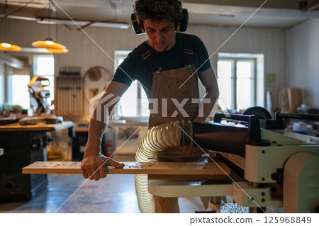 Concentrated craftsman using band saw machine in studio, finalizing project for customer handover Concentrated craftsman using band saw machine in studio, finalizing project for customer handover 125968849