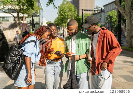 Diverse African American student friends discussing plans on smartphones, deciding where to hang out 125968996
